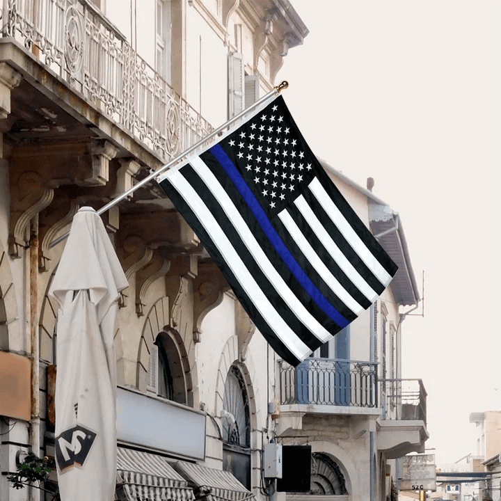 A durable Jetlifee 3×5 Ft Embroidery Black White Thin Blue Line American Flag, Made in the USA, is displayed outside a building.