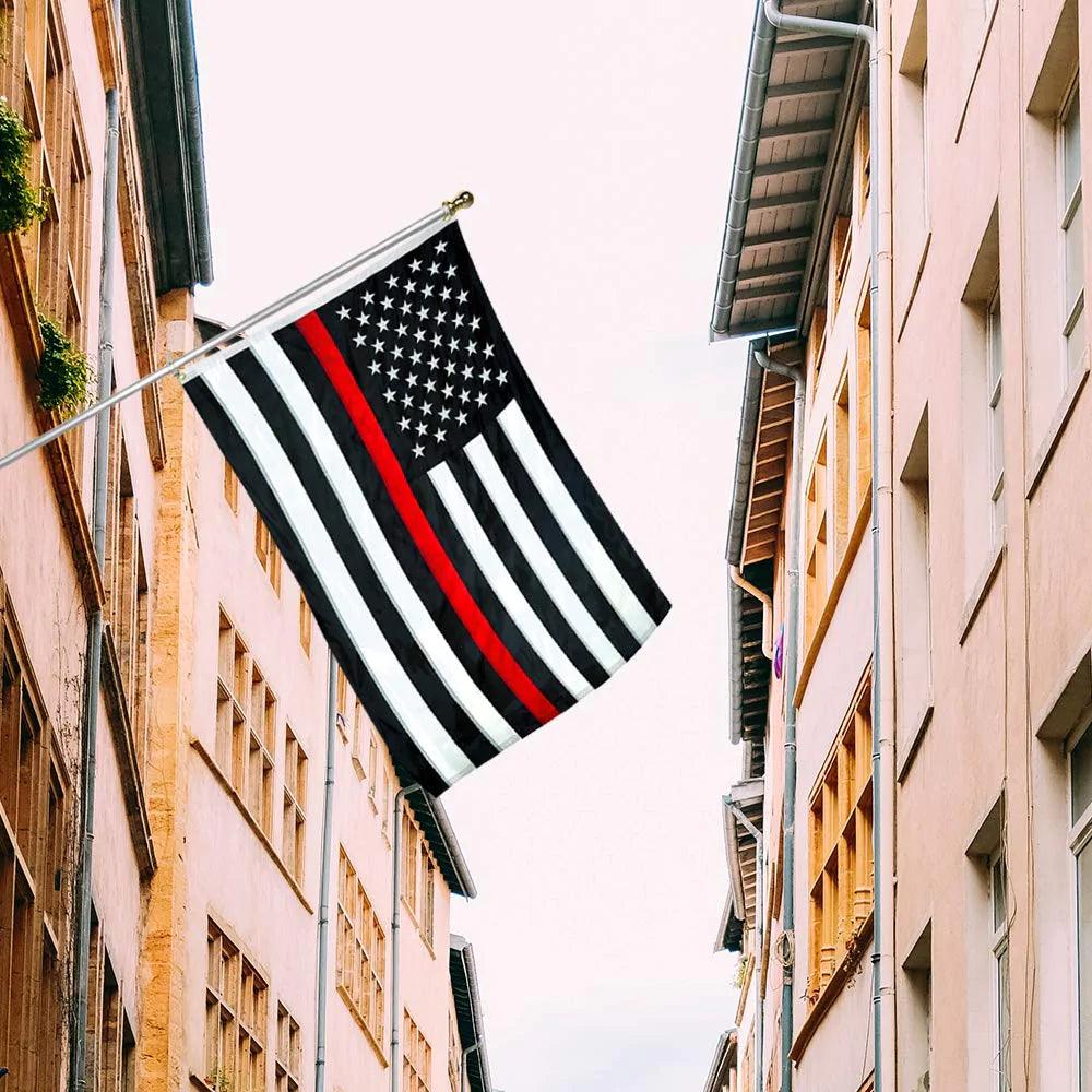 A 3×5 Ft Embroidery Black White Thin Red Line American Flag made by Jetlifee is displayed on a flagpole between buildings on a narrow street.