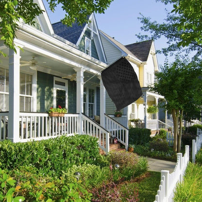 A row of colorful houses with porches and well-kept gardens under a clear sky, with a 3×5 FT Embroidery All Black American Flag made by Jetlifee hanging from one of the porches.