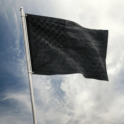 Atop a silver flagpole against a cloudy sky, the Jetlifee 3×5 FT Embroidery All Black American Flag Made in USA, featuring durable polyester and embroidered stars, proudly flies.