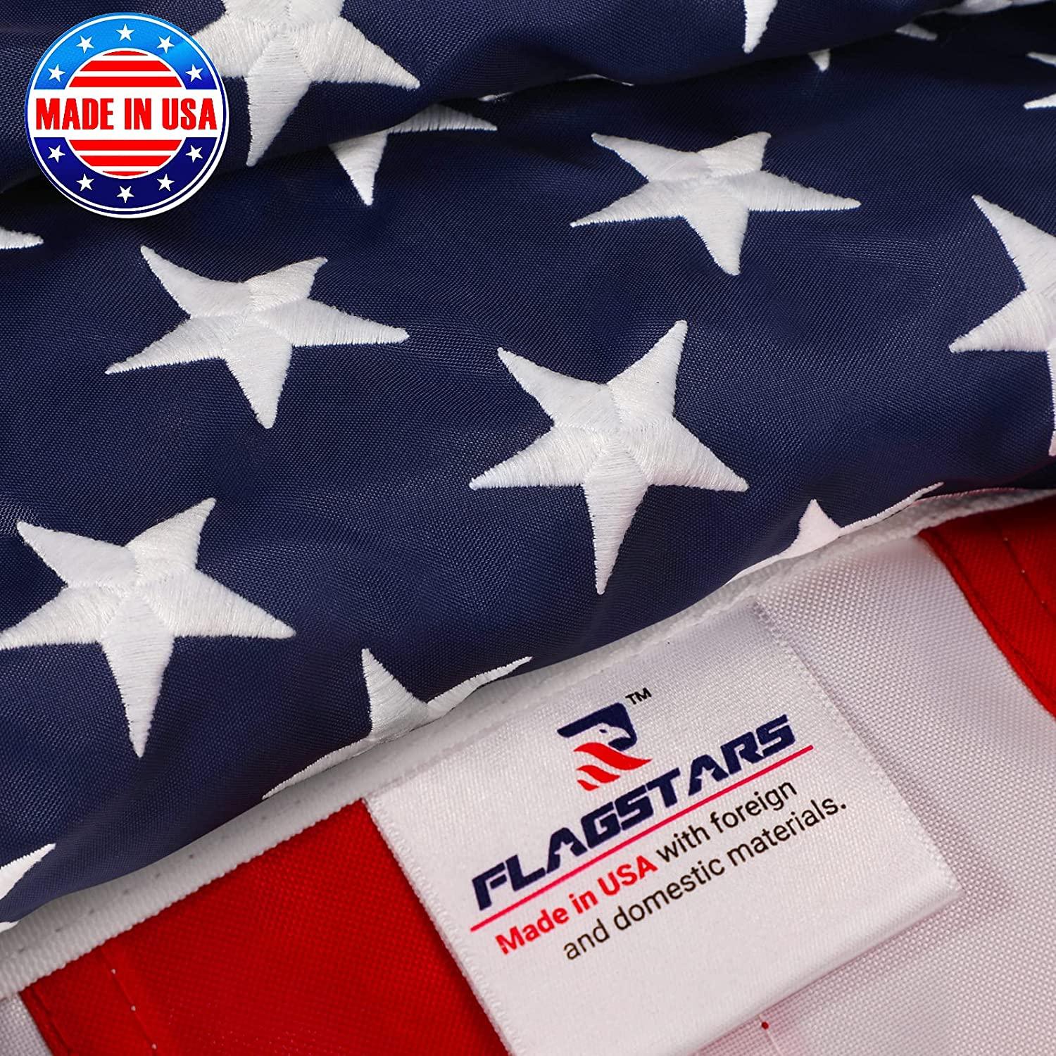 Close-up of an American flag with a label showing "FLAGSTARS - Made in USA with foreign and domestic materials" and a logo featuring "Made in USA" text over a circular emblem. The Jetlifee American Flag Pole Kit boasts an easy-to-assemble, never tangle design for your convenience, including a 6FT 5-section flag pole.